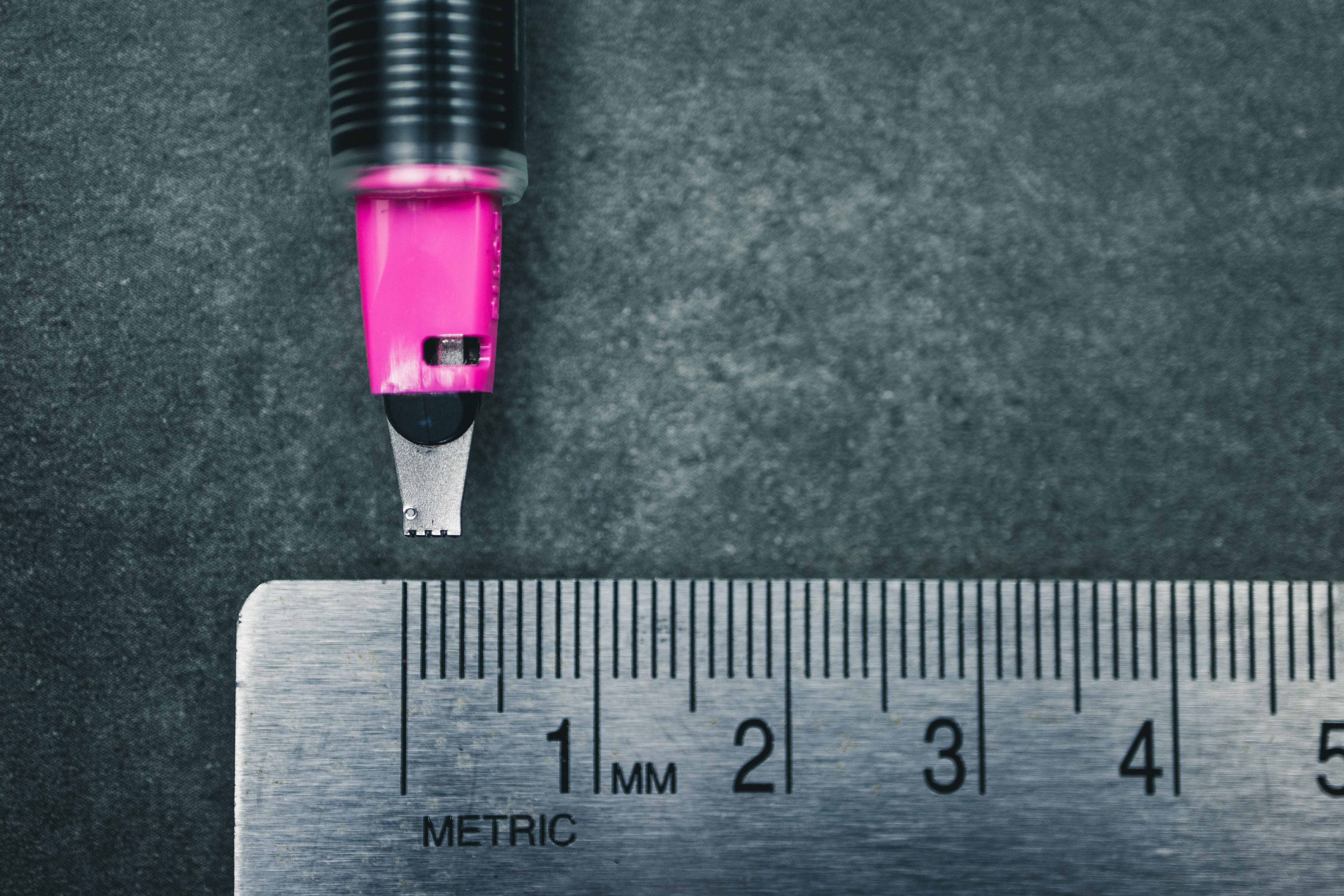 pilot-parallel-3mm-pink-nib-closeup-pen-ruler Closeup of 3mmm pink pilot parallel pen nib measured against a metal ruler on a grey tabletop