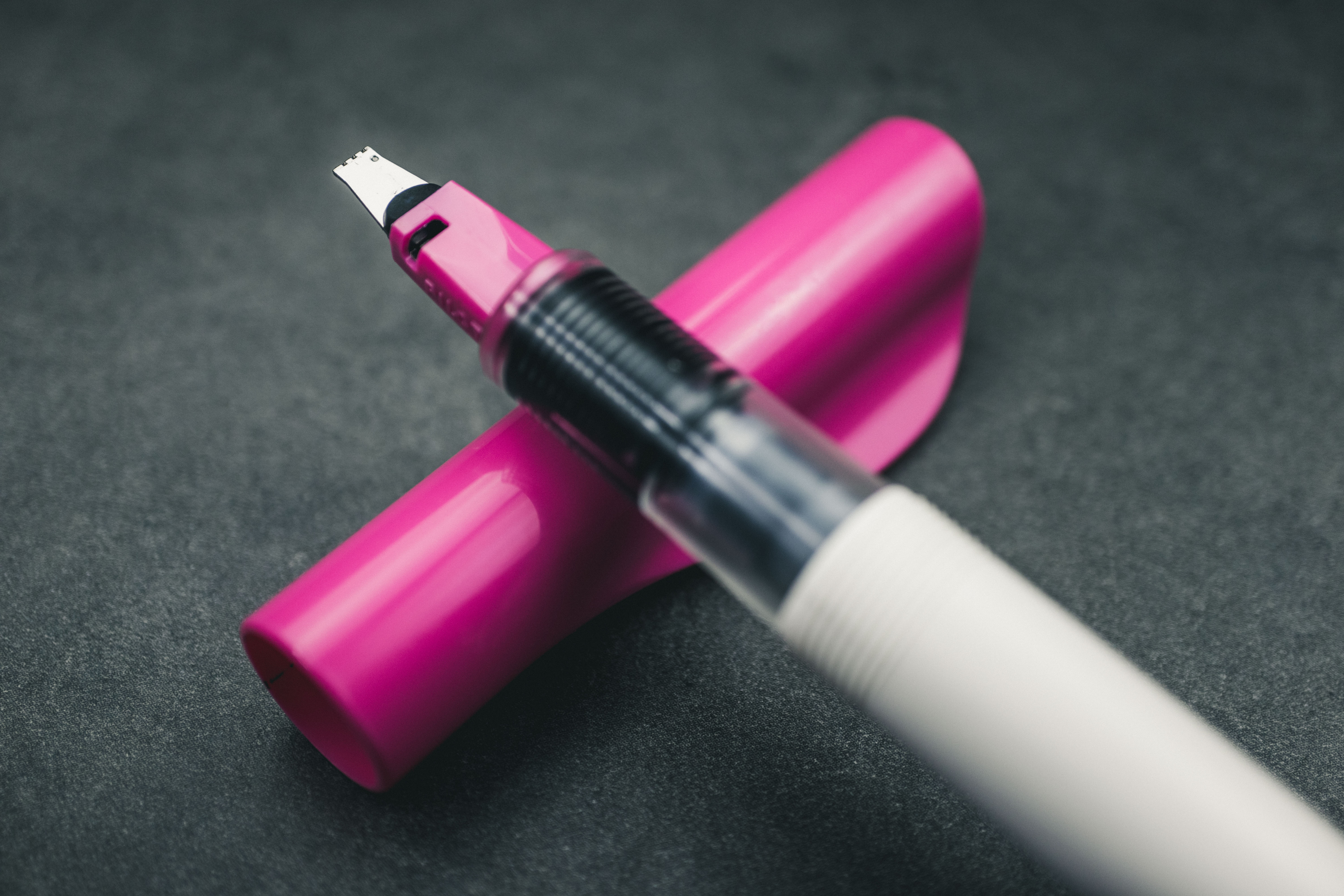 3mm-Pink-Pilot-Parallel-pen-nib-closeup Super closeup of pink 3mm Pilot Parallel pen nib and pen section resting on pen cap and a gey granite surface