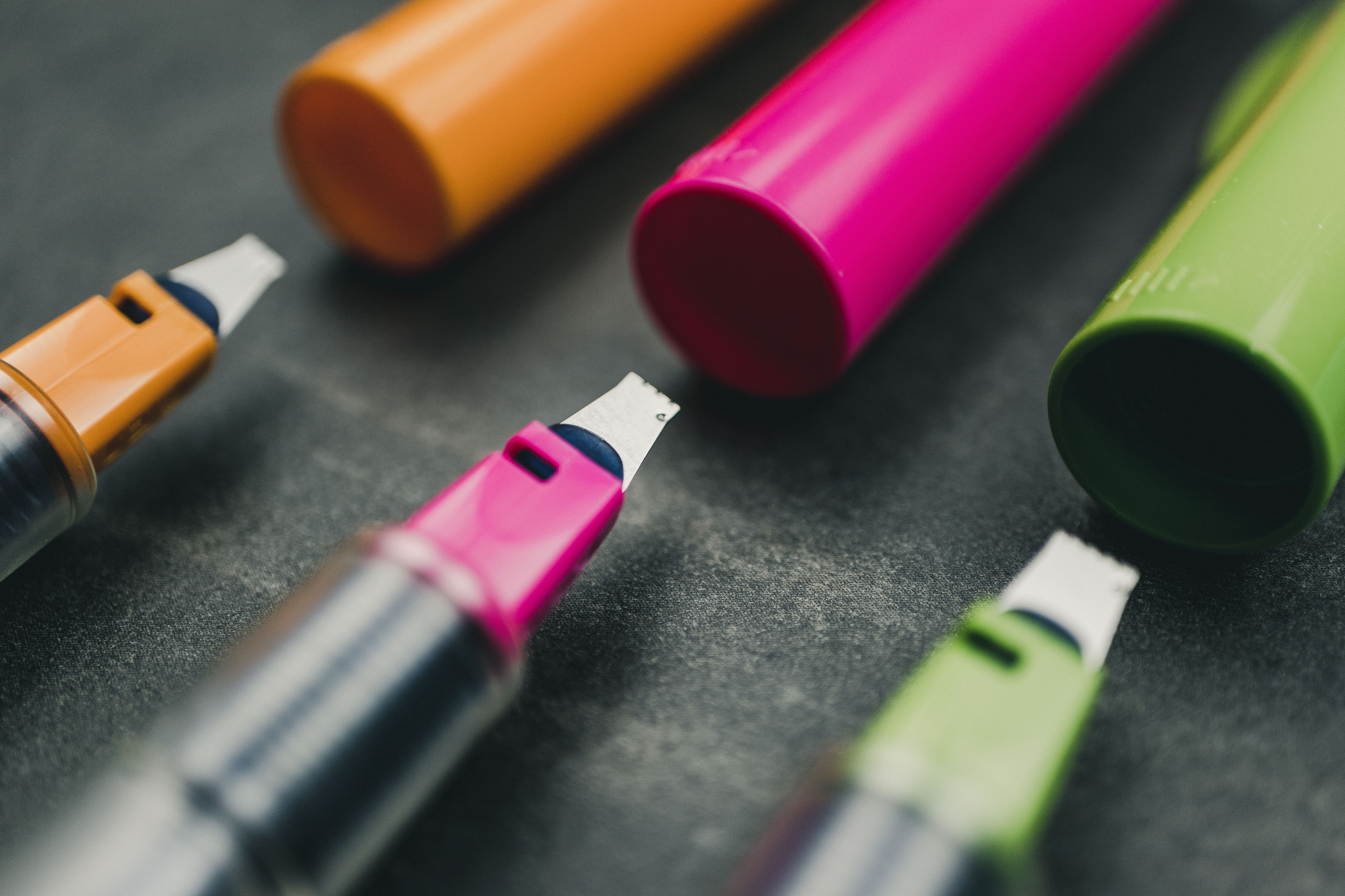 pilot-parallel-3mm-pink-pem-compared-with-green-orange-sizes Super closeup comparison of 3mm, 2.4mm, and 3.8mm pilot parallel orange, green, and pink pens with caps resting on a grey countertop